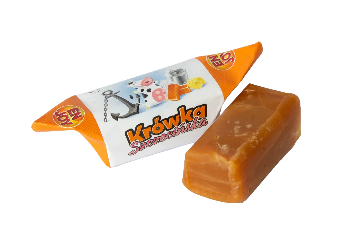 Krówka Szczecińska w pomarańczowo-białym papierku, obok odwinięta kostka krówki
